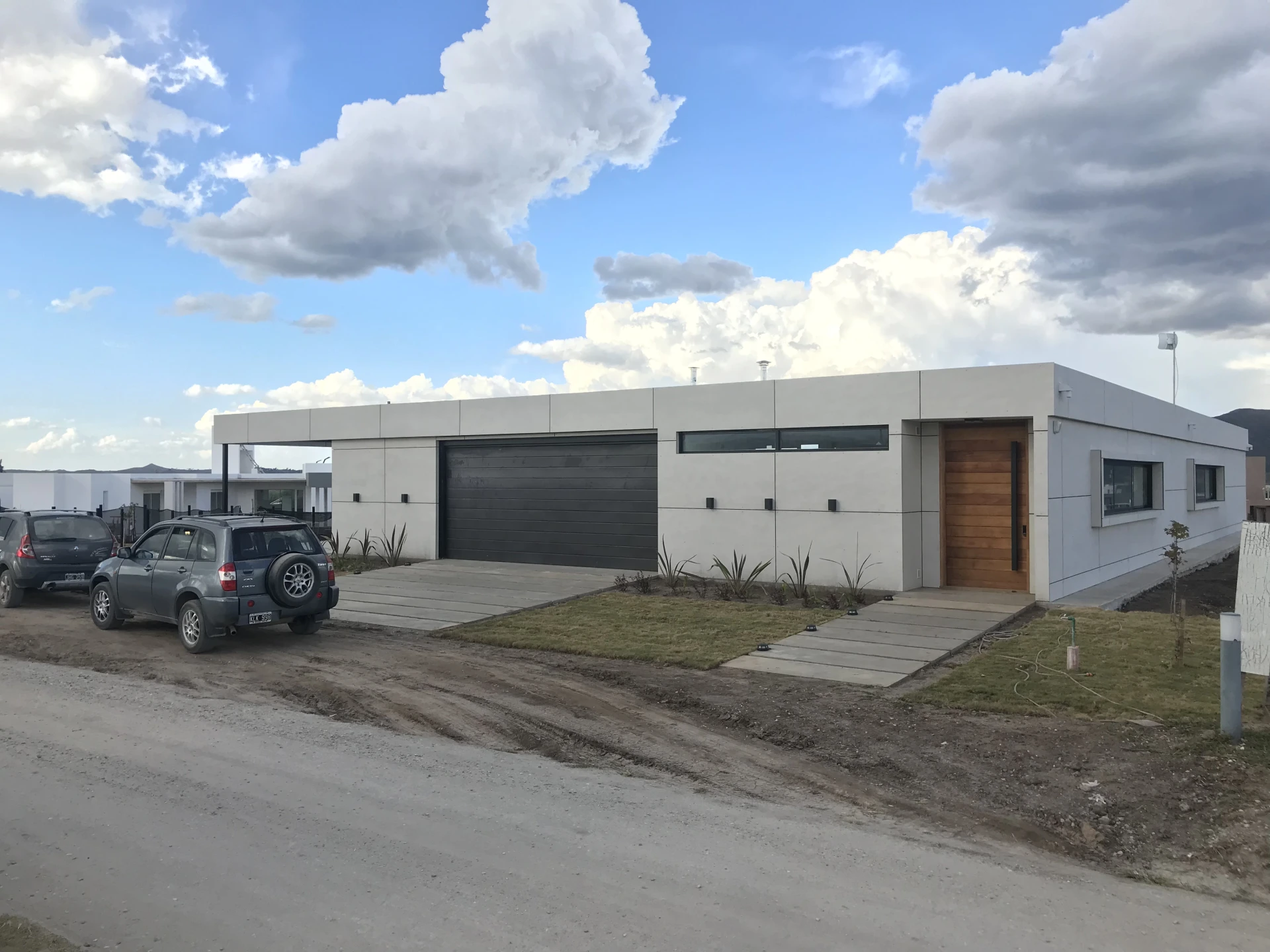 Foto de una casa en puerto del Águila construída con el sistema de Steel Framing por Vértice Construcciones en la que se observa la fachada de la casa revestida con doble placa marca Equitone y la puerta principal y el garage, desde el ángulo derecho de la casa