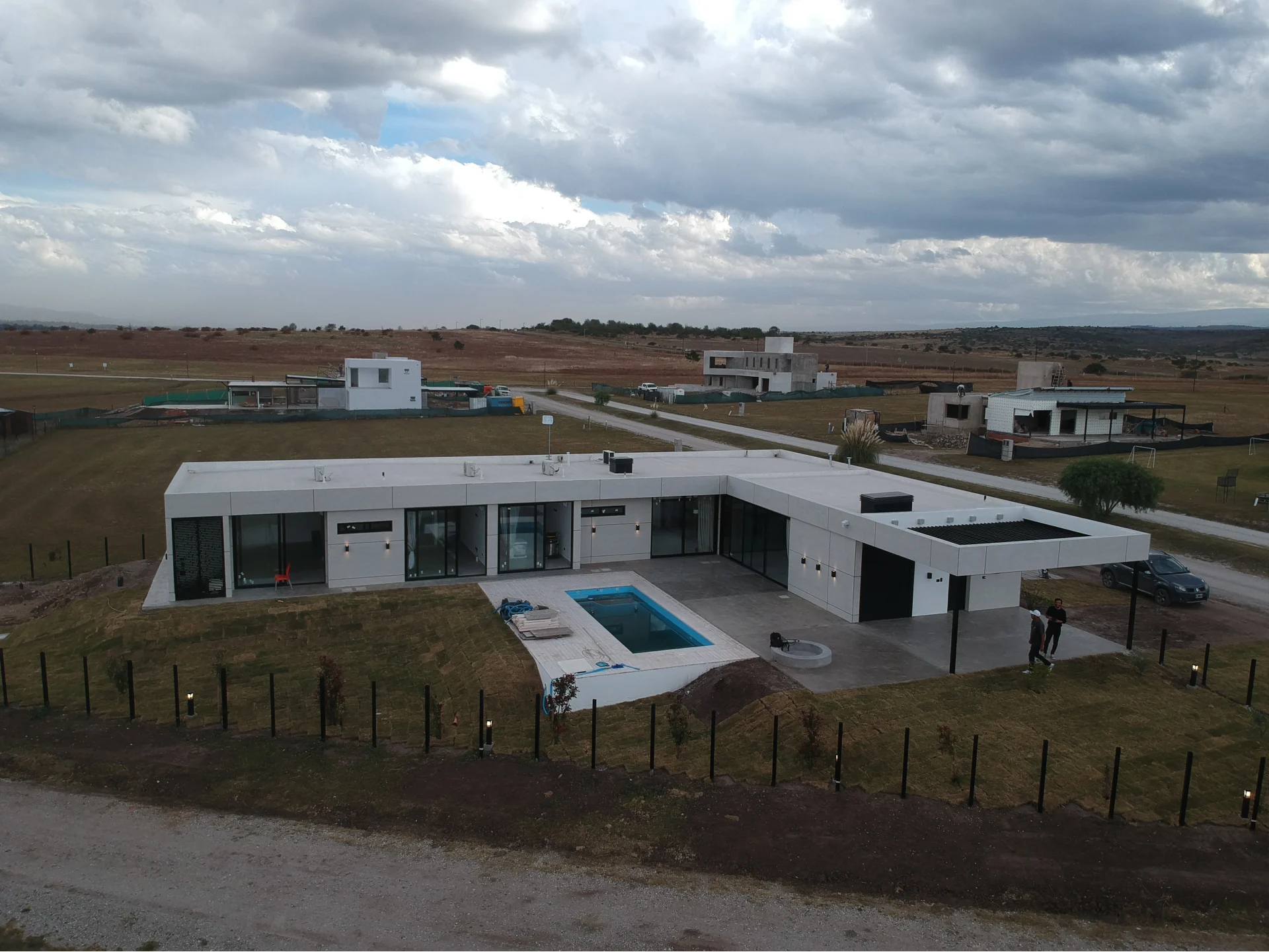 Foto de una casa en puerto del Águila construída con el sistema de Steel Framing por Vértice Construcciones en la que se observa una galería en forma de L y el patio trasero más la pileta de la casa revestida con doble placa marca Equitone