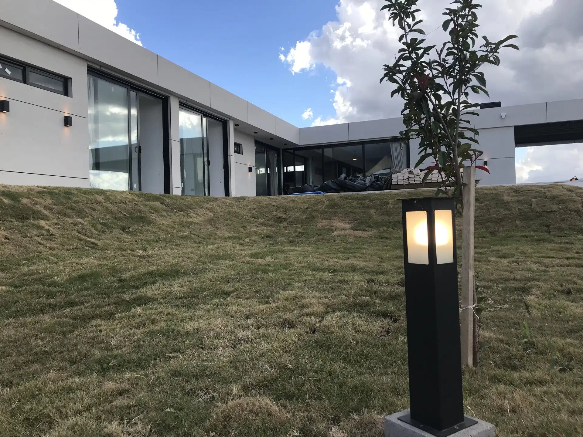 Foto de una casa en puerto del Águila construída con el sistema de Steel Framing por Vértice Construcciones en la que se observa en primer plano el patio trasero y más atrás una galería en forma de L de la casa revestida con doble placa marca Equitone