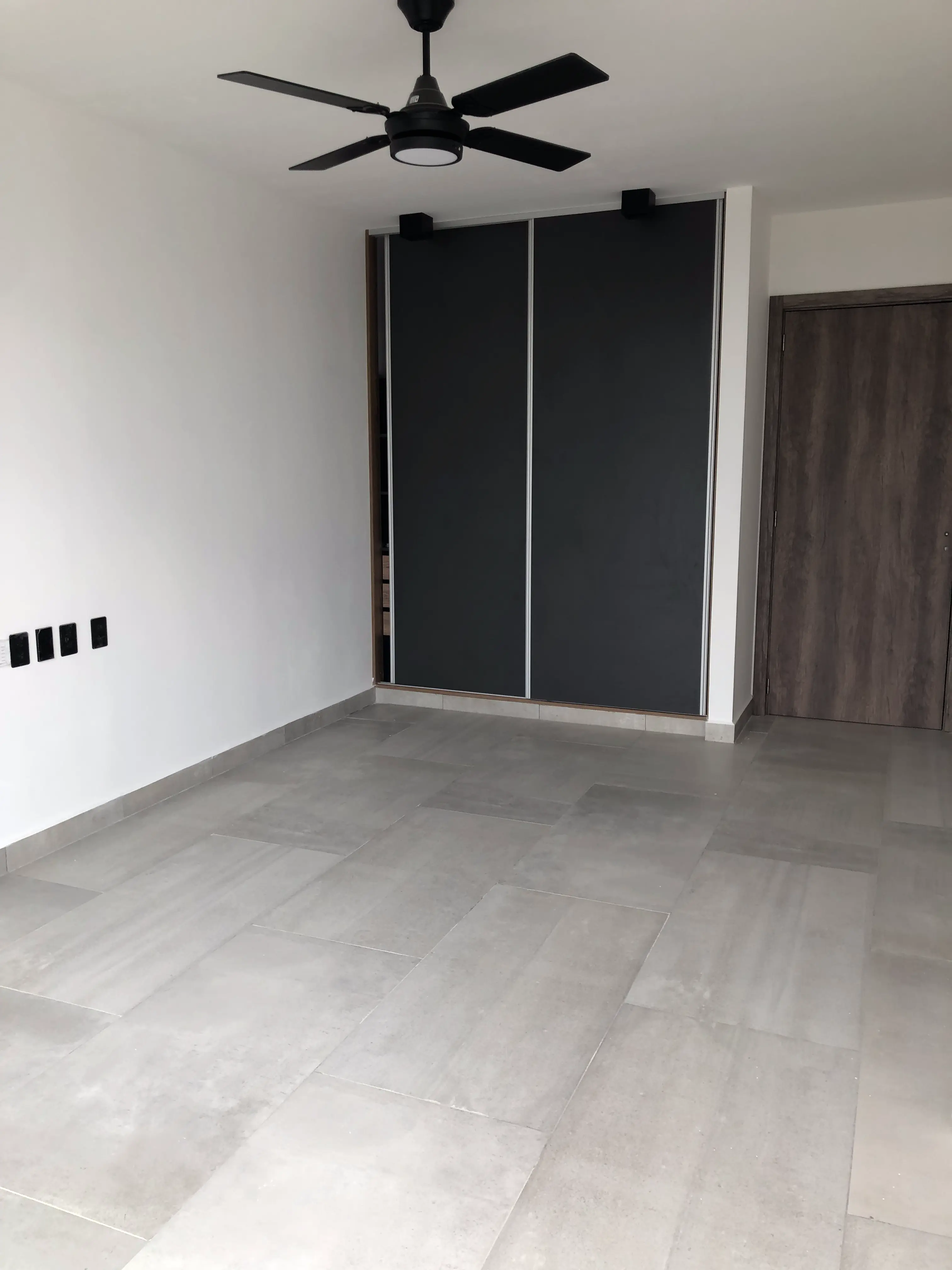 Foto de una casa en puerto del Águila construída con el sistema de Steel Framing por Vértice Construcciones en la que se observa un dormitorio con piso de cerámico, un placard y un ventilador de techo color negro que hace juego con las luces de techo