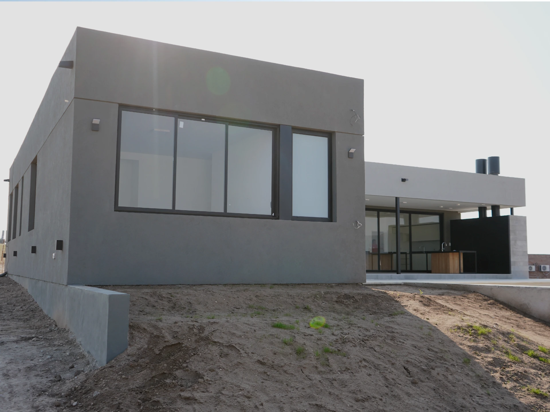 Foto de una casa en puerto del Águila construída con el sistema de Steel Framing por Vértice Construcciones en la que se observa la fachada frontal del lado izquierdo de la casa revestida con el sistema EIF's dándole una terminación final con revestimiento texturado