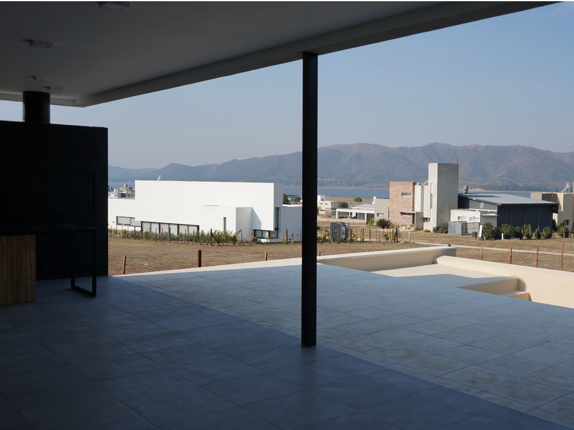 Foto de una casa en puerto del Águila construída con el sistema de Steel Framing por Vértice Construcciones en la que se observa la galería de la casa con un asador y una mesada tipo barra y una pileta pegada a esa galería