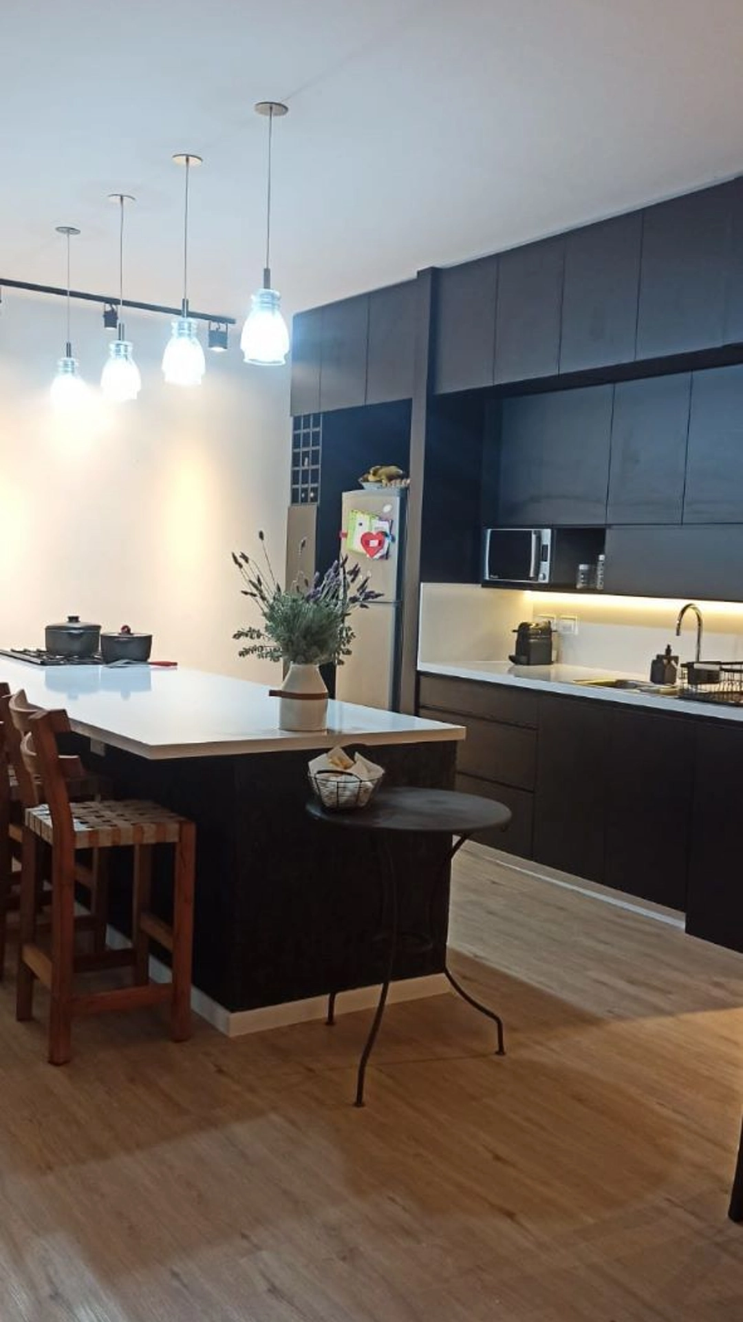 Foto de una casa en 7 Soles construída con el sistema de Steel Framing por Vértice Construcciones en la que se observa la cocina con muebles de madera marrón oscuro y una isla al centro con una mesada alta tipo barra y sillas altas