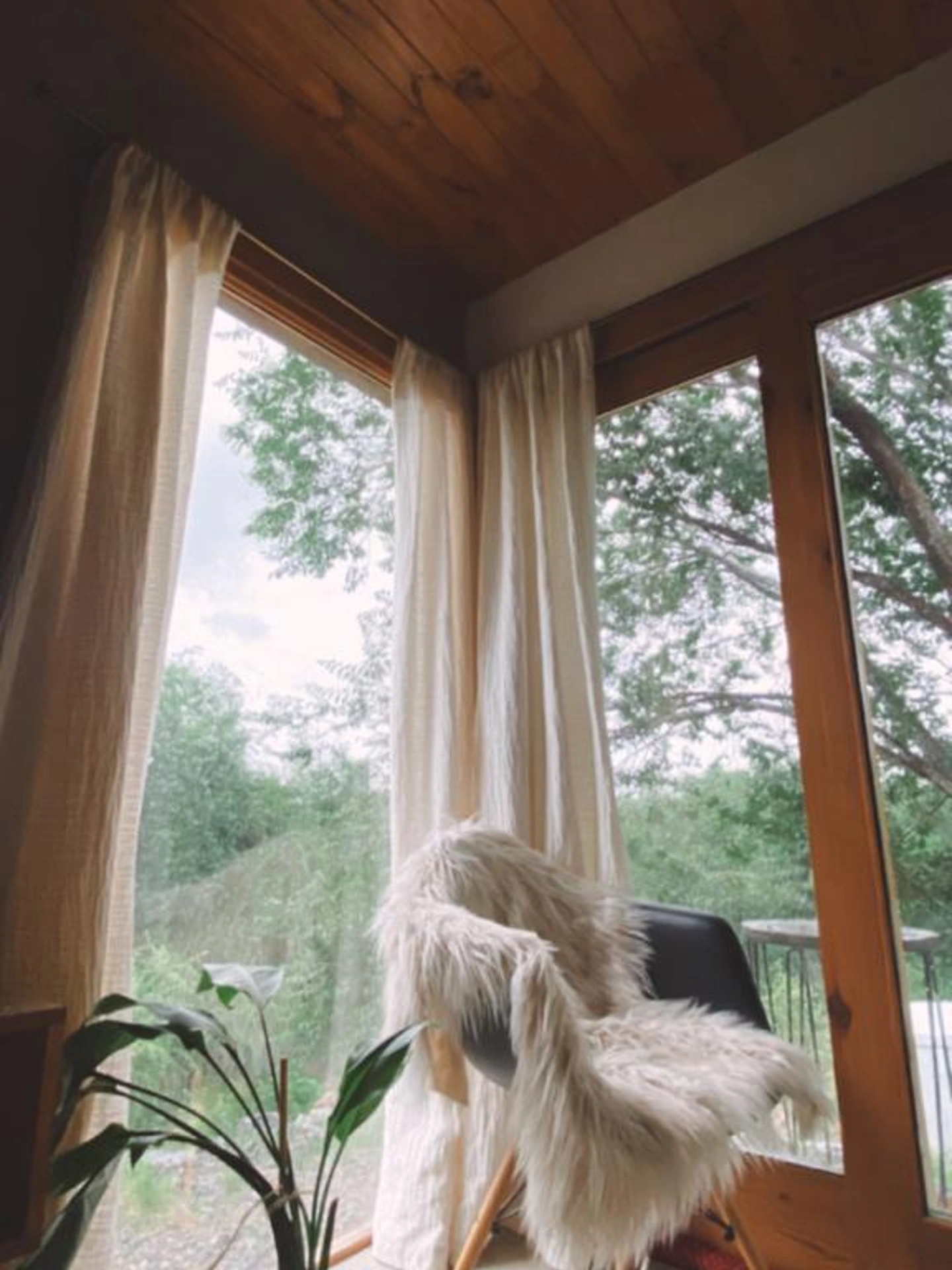 Foto de una casa en Bialet Massé construída con el sistema de Steel Framing por Vértice Construcciones en la que se observa un ángulo interior de la casa con ventanas de piso a techo con aberturas de madera y una silla