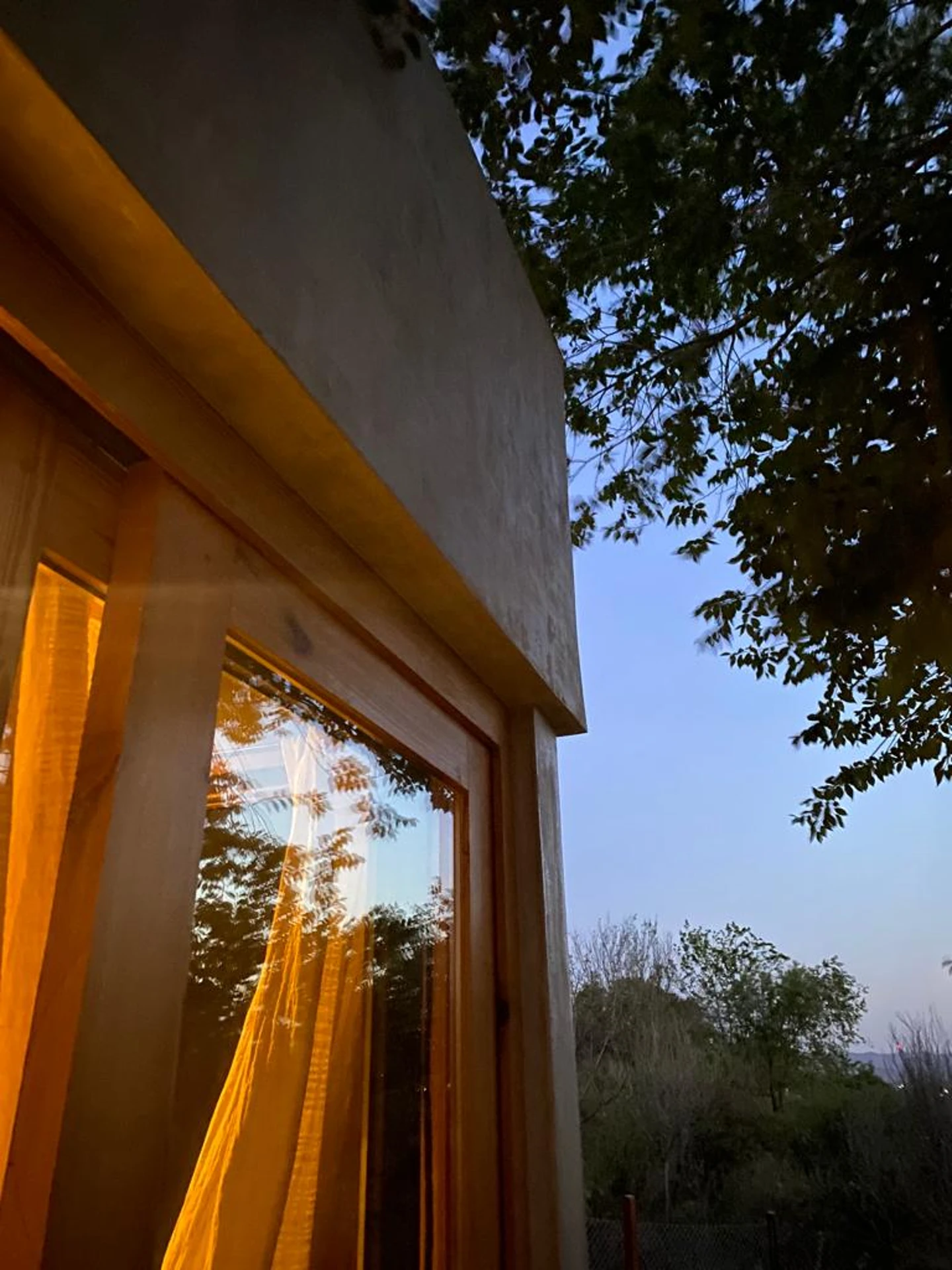 Foto de una casa en Bialet Massé construída con el sistema de Steel Framing por Vértice Construcciones en la que se observa un ángulo exterior de la casa con ventanas con abertura de madera y un acabado símil hormigón visto