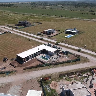 Foto de una casa recién terminada de construir tomada desde arriba con un drone en la que también se observan las calles y otras casas y terrenos valdíos