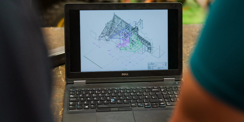 Foto de una computadora laptop en la que se visualiza un plano de una estructura con perfiles en 3D